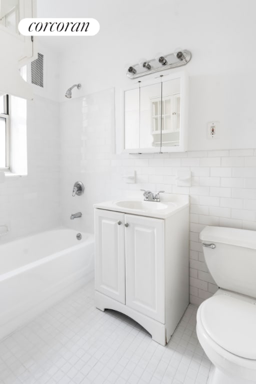 full bathroom featuring tile walls, vanity, tiled shower / bath combo, and toilet