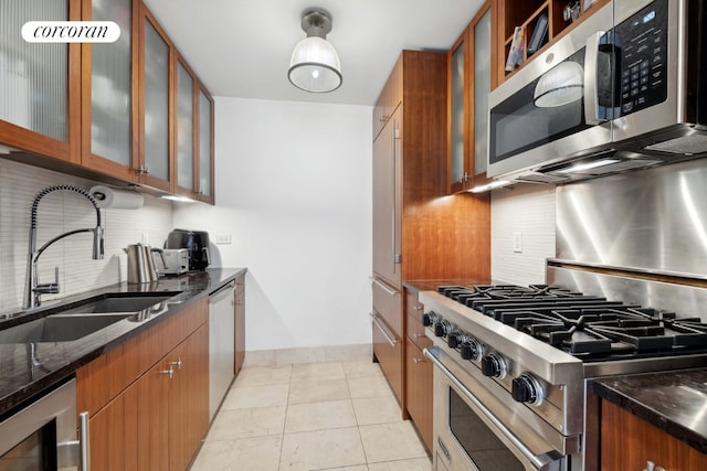 kitchen with sink, dark stone counters, stainless steel appliances, beverage cooler, and backsplash