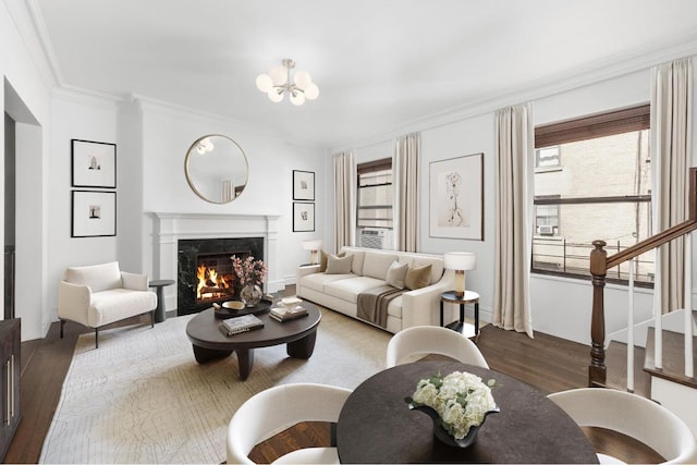 living room featuring an inviting chandelier, dark wood-type flooring, ornamental molding, and a fireplace