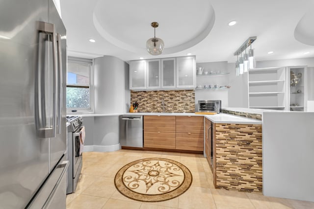 kitchen with light countertops, appliances with stainless steel finishes, glass insert cabinets, and decorative light fixtures