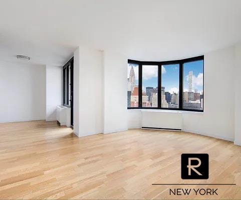 unfurnished room featuring a city view and wood finished floors