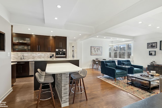 kitchen featuring stainless steel appliances, a breakfast bar, wood finished floors, and light countertops