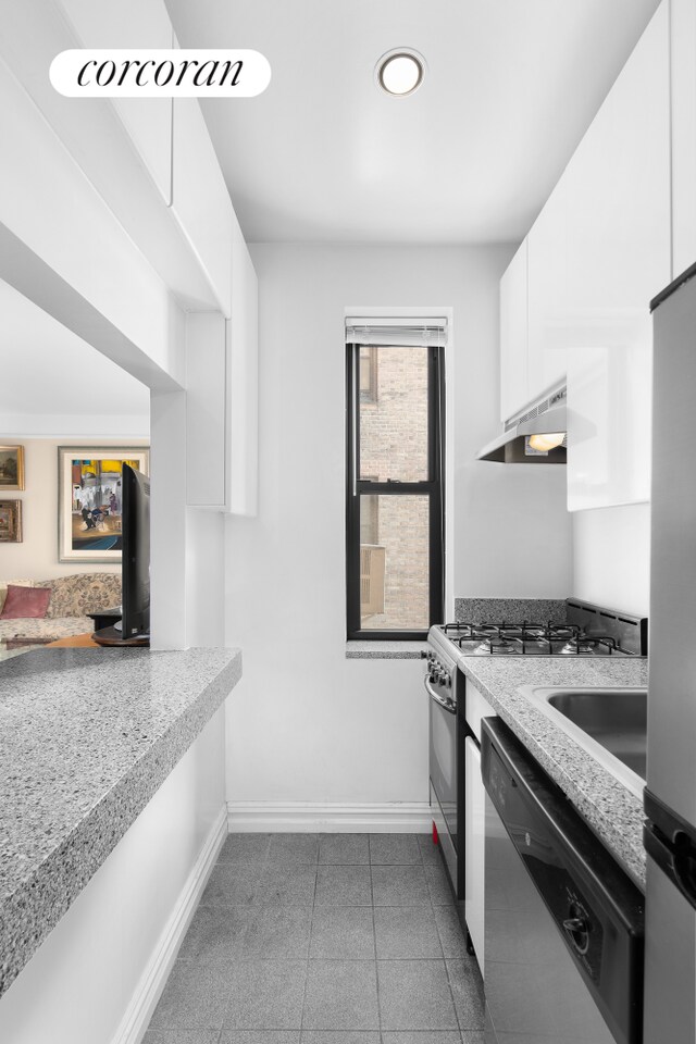 402 E 74th St Unit 4D, New York City, NY 10021 - kitchen with dark tile patterned floors, appliances with stainless steel finishes, baseboards, under cabinet range hood, and white cabinetry