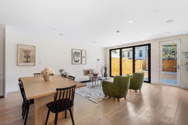 dining area with light wood-style floors, a healthy amount of sunlight, and baseboards