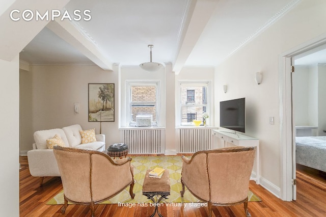 living room featuring beamed ceiling, ornamental molding, radiator, and light wood-type flooring