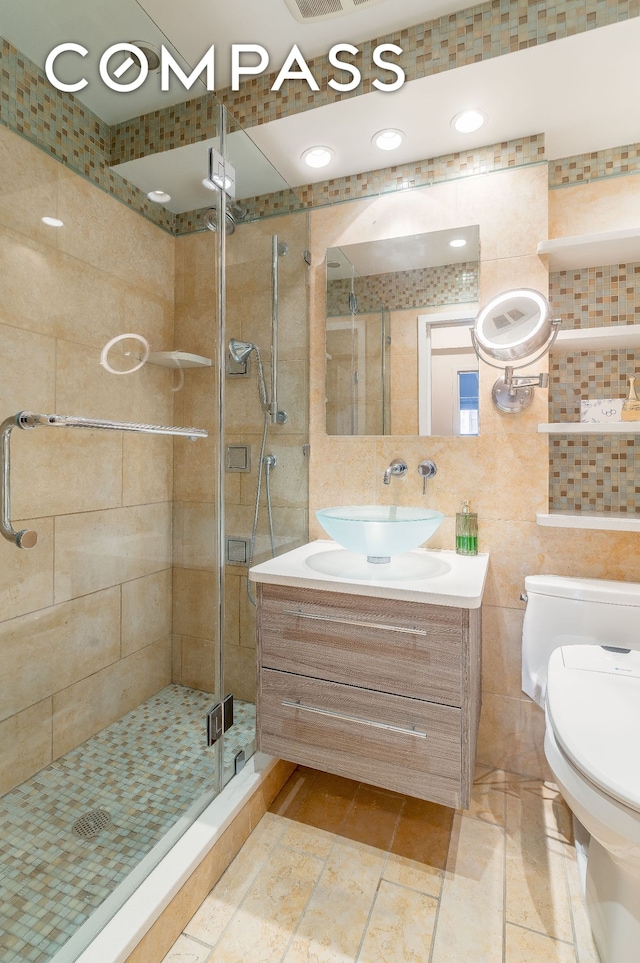 bathroom featuring tile walls, vanity, toilet, and a stall shower