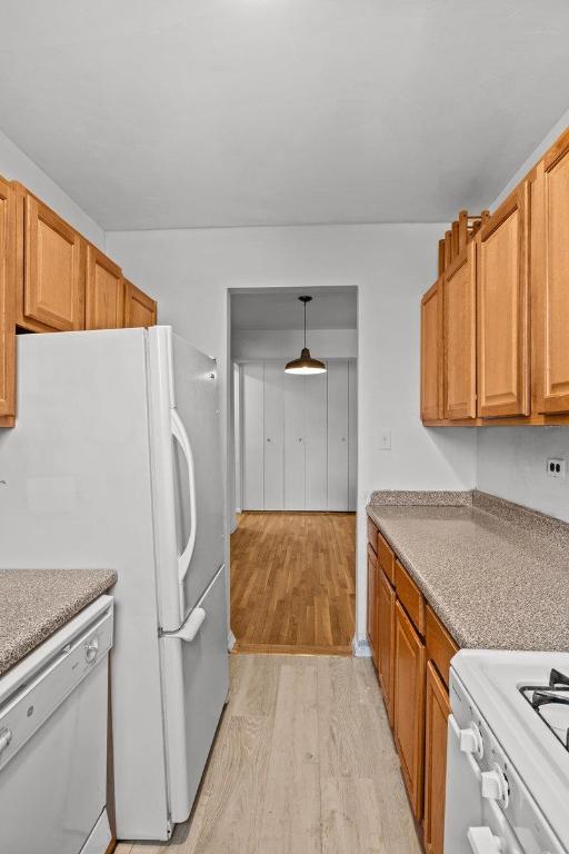 kitchen featuring hanging light fixtures, light wood-type flooring, and white appliances