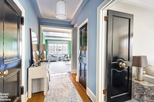 corridor with ornamental molding, baseboards, and wood finished floors