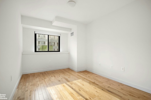 spare room featuring baseboards, visible vents, and light wood-style floors