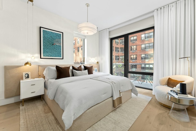 bedroom with access to exterior, multiple windows, and wood finished floors