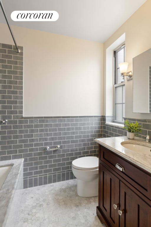 bathroom featuring tile walls, vanity, and toilet