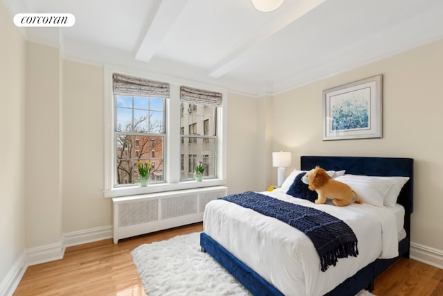 bedroom with radiator, wood-type flooring, and beamed ceiling