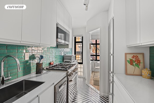 kitchen featuring a sink, white cabinetry, appliances with stainless steel finishes, backsplash, and modern cabinets