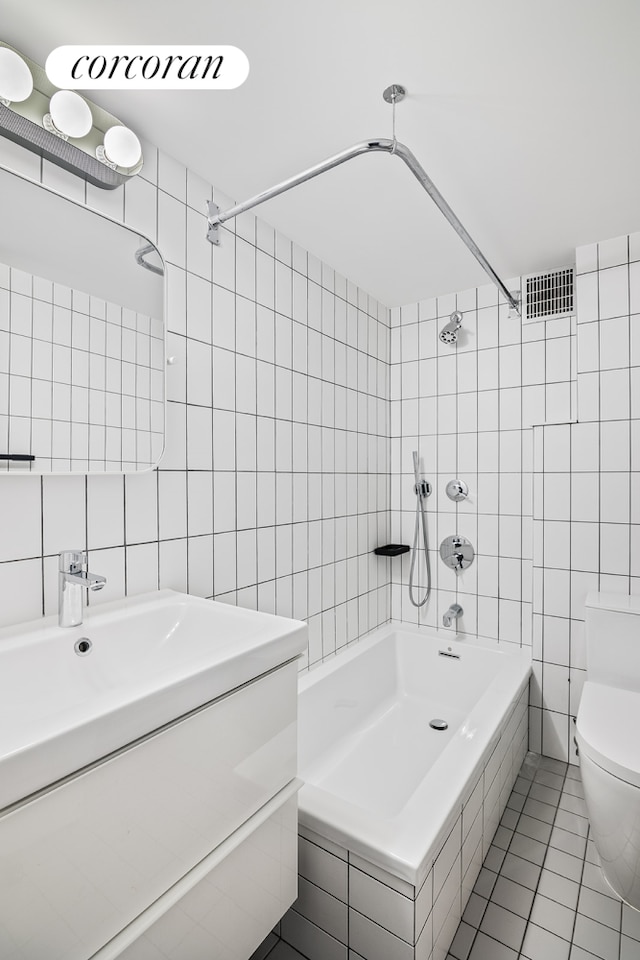 full bathroom with tile patterned flooring, tile walls, toilet, and visible vents