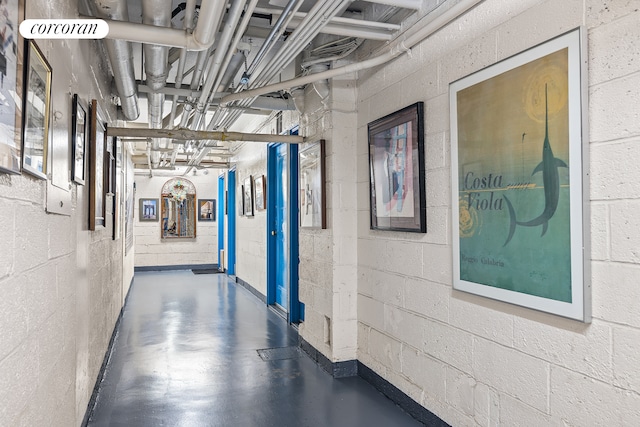 hallway featuring concrete block wall and finished concrete flooring