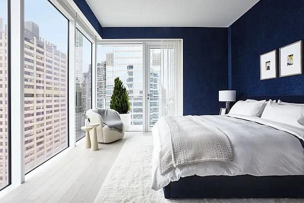 bedroom with access to exterior, multiple windows, wood finished floors, and a city view