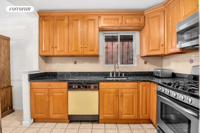 kitchen featuring visible vents, brown cabinetry, appliances with stainless steel finishes, dark stone countertops, and a sink