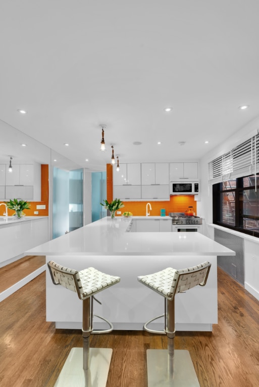 kitchen with a spacious island, white cabinets, a breakfast bar area, and high end range