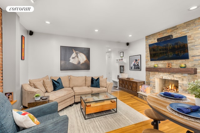 living room featuring a stone fireplace and light hardwood / wood-style floors