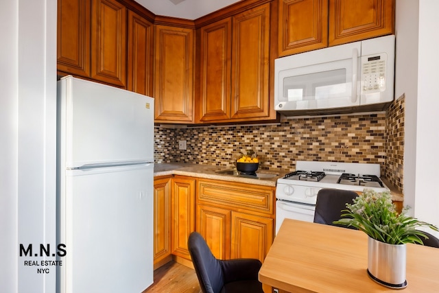 kitchen featuring brown cabinets, white appliances, light countertops, and backsplash