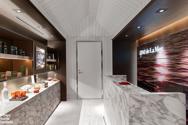 bar with light stone counters and vaulted ceiling