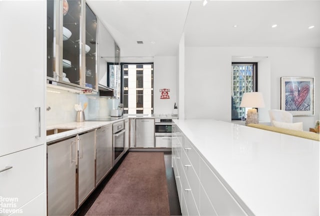 kitchen featuring sink, white cabinetry, tasteful backsplash, kitchen peninsula, and black electric stovetop