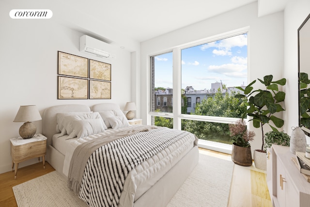 bedroom featuring light hardwood / wood-style flooring and a wall unit AC