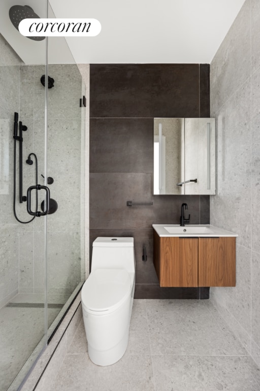 bathroom featuring an enclosed shower, tile patterned floors, toilet, tile walls, and vanity