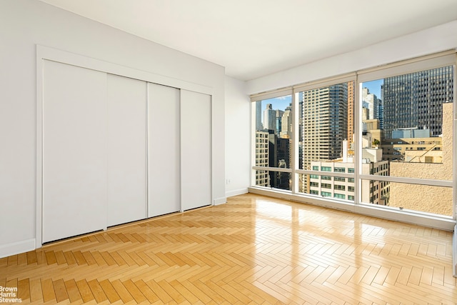 unfurnished bedroom with a view of city, baseboards, and a closet