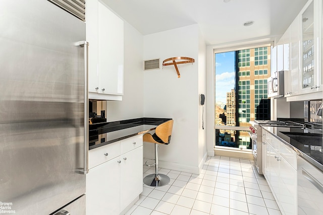 kitchen featuring dark countertops, visible vents, white cabinetry, and high quality appliances