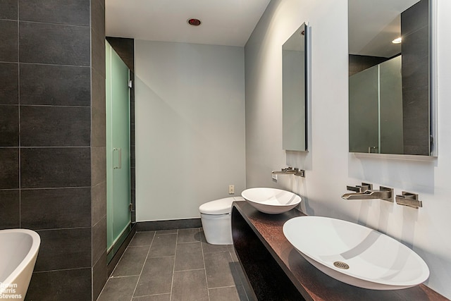 full bathroom with tile patterned floors, a soaking tub, toilet, and a sink