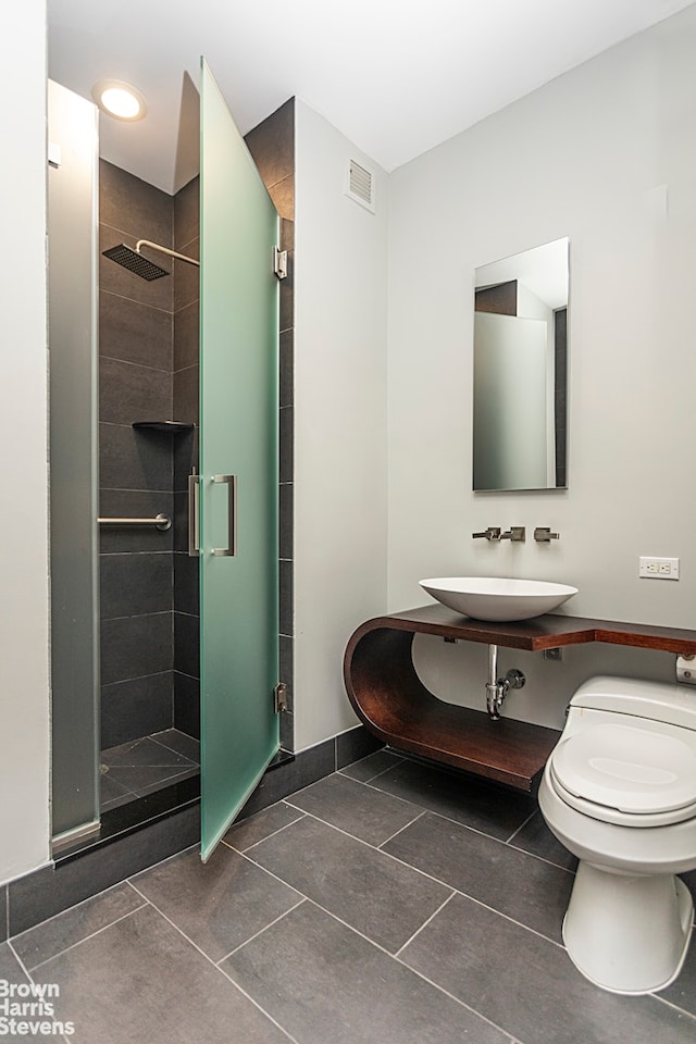 bathroom featuring visible vents, toilet, a stall shower, tile patterned floors, and a sink