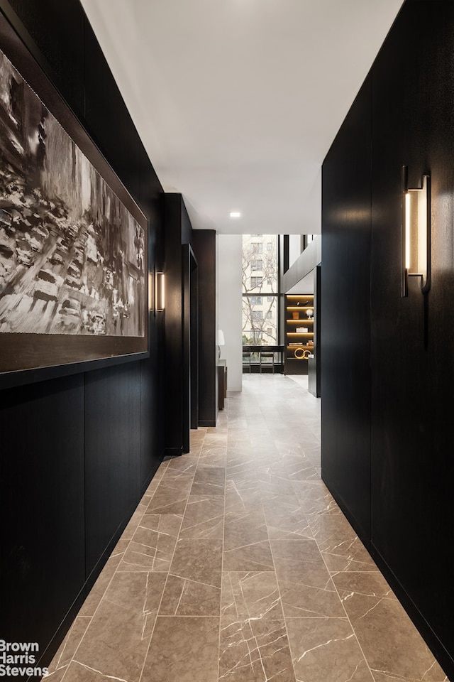 corridor with marble finish floor and a wall of windows