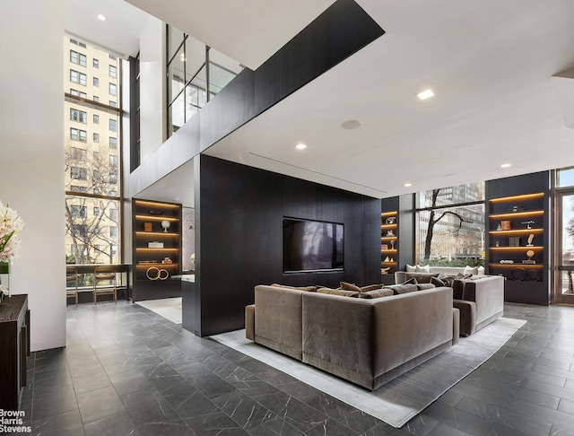 living room featuring built in features, a healthy amount of sunlight, and a wall of windows