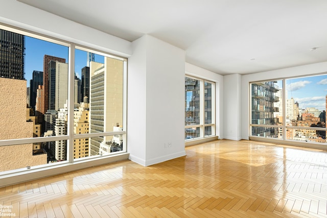 unfurnished room featuring a view of city and baseboards