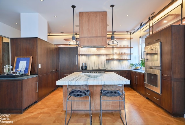 kitchen featuring a kitchen island, appliances with stainless steel finishes, pendant lighting, a kitchen bar, and open shelves