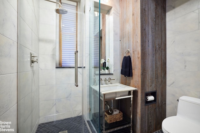 bathroom with toilet, a stall shower, and tile walls