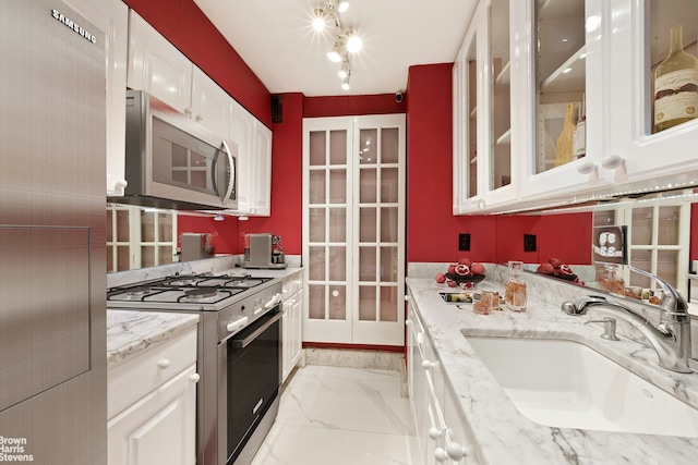 kitchen featuring white cabinets, stainless steel appliances, marble finish floor, and a sink