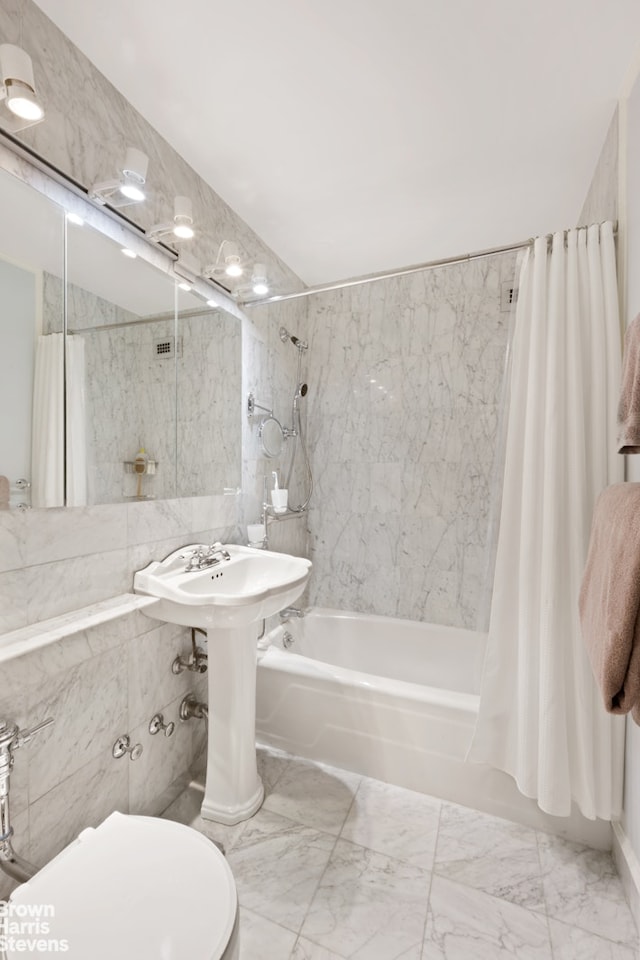 bathroom featuring toilet, shower / bath combination with curtain, marble finish floor, and a sink
