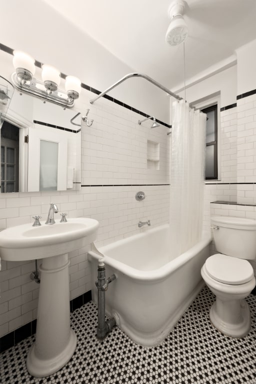 bathroom featuring shower / bath combination with curtain, tile patterned floors, toilet, and tile walls