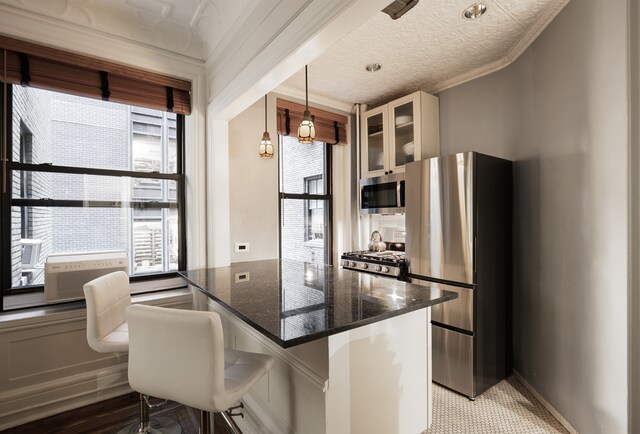 kitchen featuring crown molding, appliances with stainless steel finishes, decorative light fixtures, and dark wood-type flooring