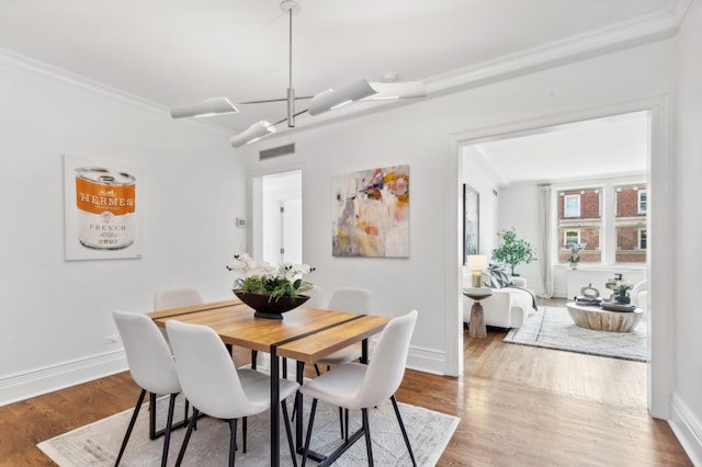 dining room featuring baseboards, ornamental molding, and wood finished floors