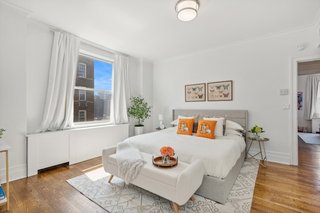 bedroom featuring crown molding, baseboards, and wood finished floors