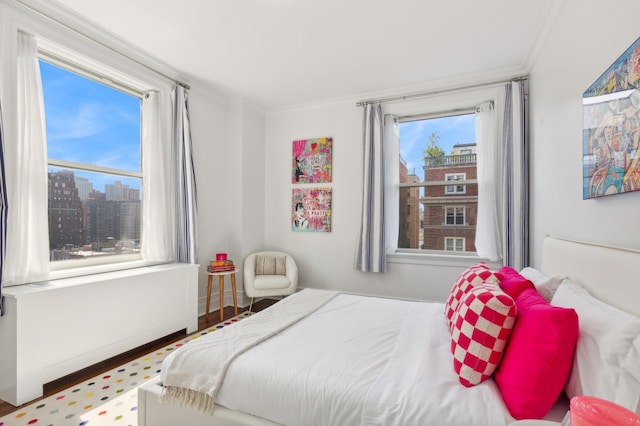 bedroom with crown molding, a view of city, and wood finished floors
