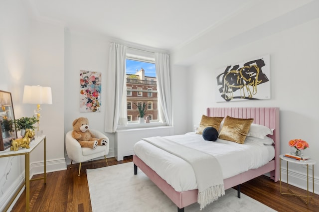 bedroom with baseboards, crown molding, and wood finished floors