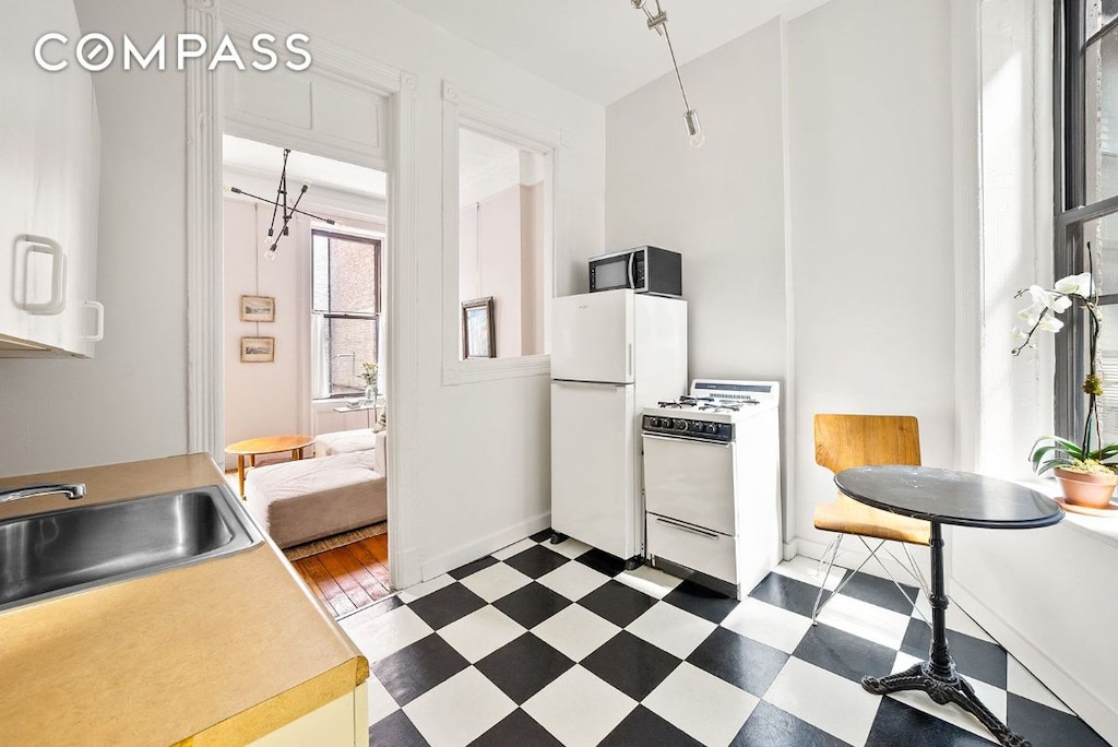 kitchen featuring dark floors, white appliances, light countertops, and a sink