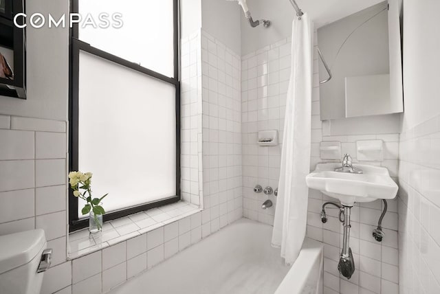 bathroom featuring toilet, shower / tub combo, plenty of natural light, and tile walls