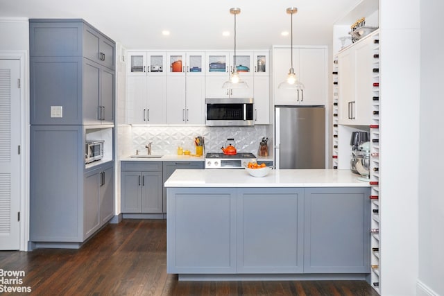 64 E 94th St Unit 3C, New York City, NY 10128 - kitchen featuring appliances with stainless steel finishes, a sink, a peninsula, gray cabinets, and glass insert cabinets