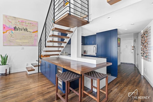 interior space featuring blue cabinetry, baseboards, dark wood-style floors, and recessed lighting