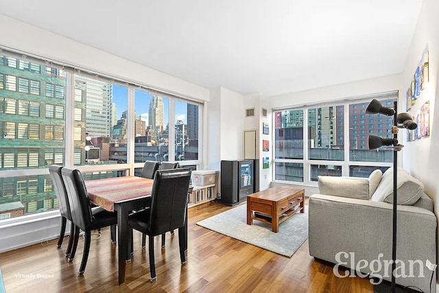 dining area featuring visible vents, a city view, and wood finished floors